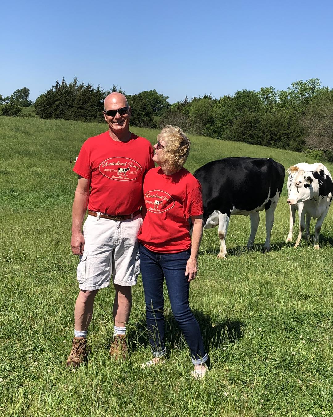 Man and woman standing in a field with cows in the background