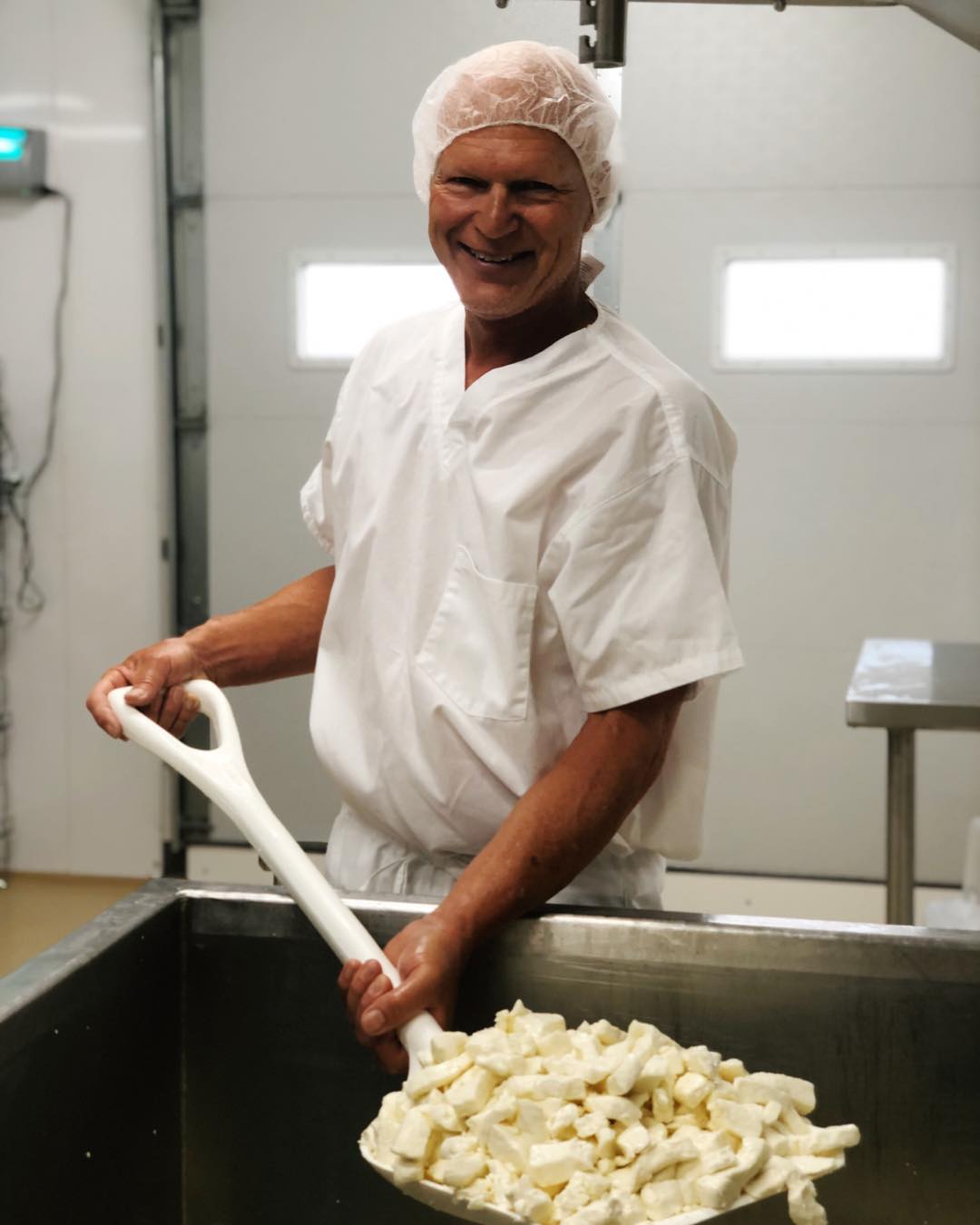 Man scooping cheese curds in a dairy