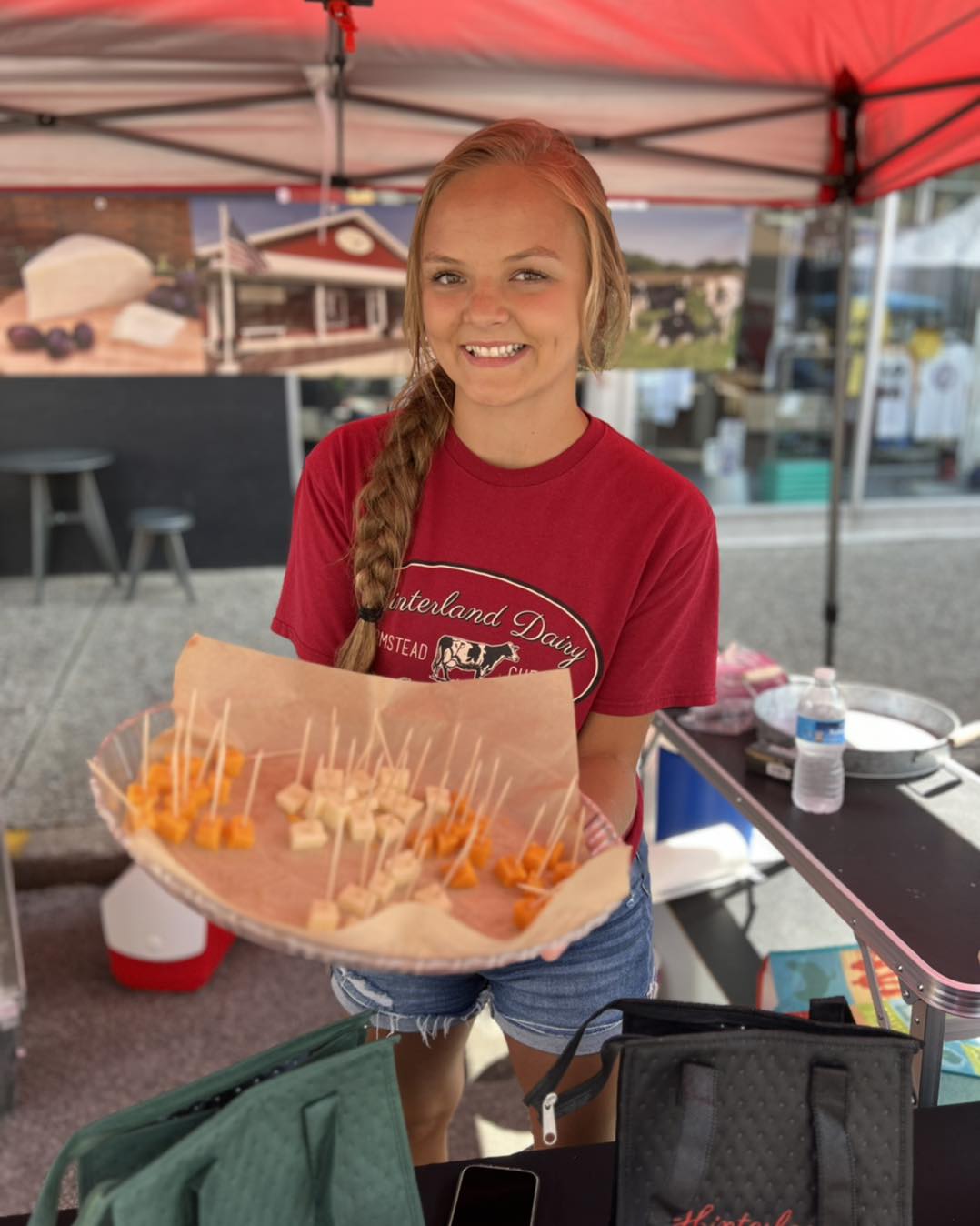 Woman holding a sampler of cheese at an outdoor market