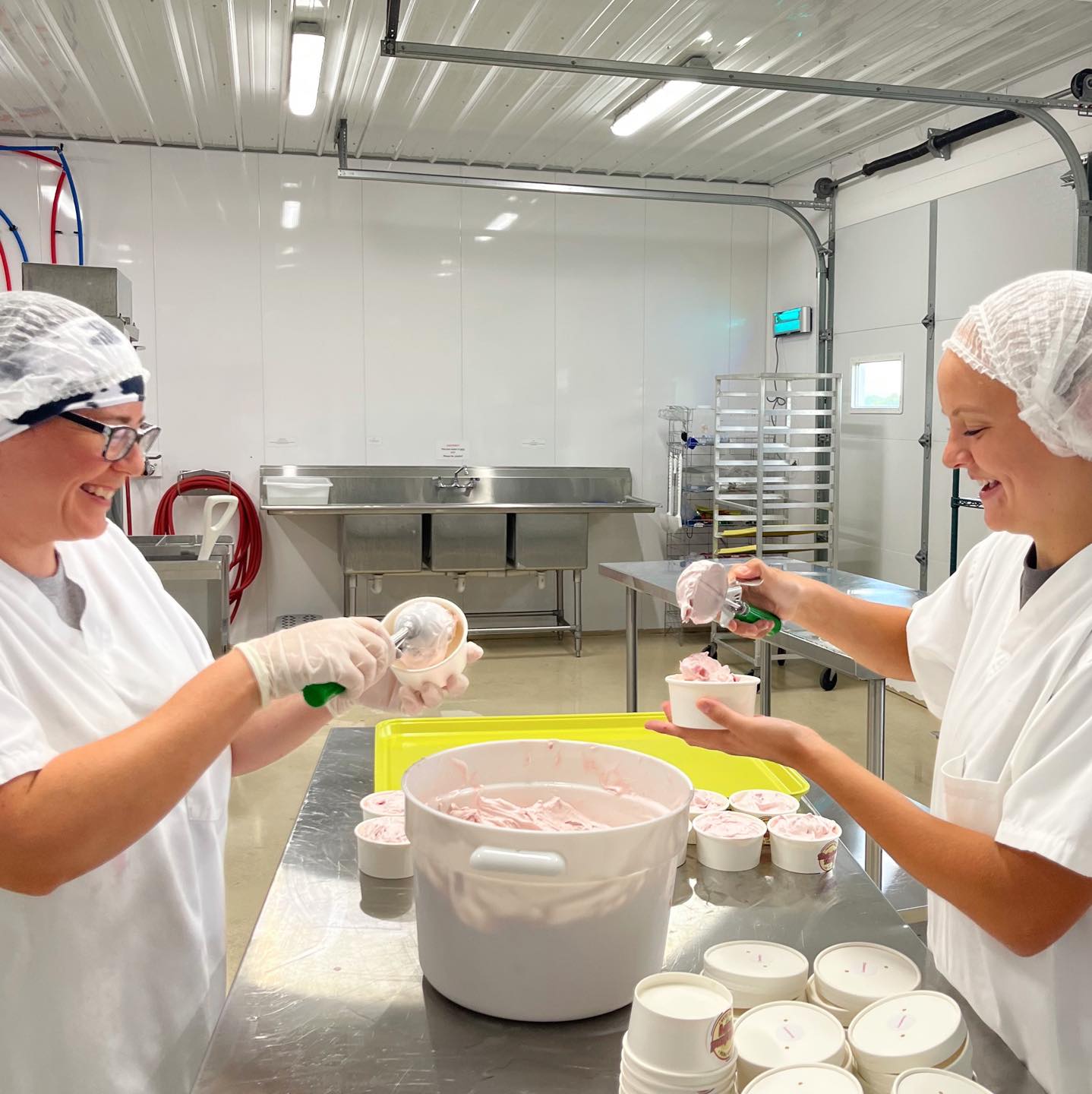 Women scooping ice cream into containers in a dair