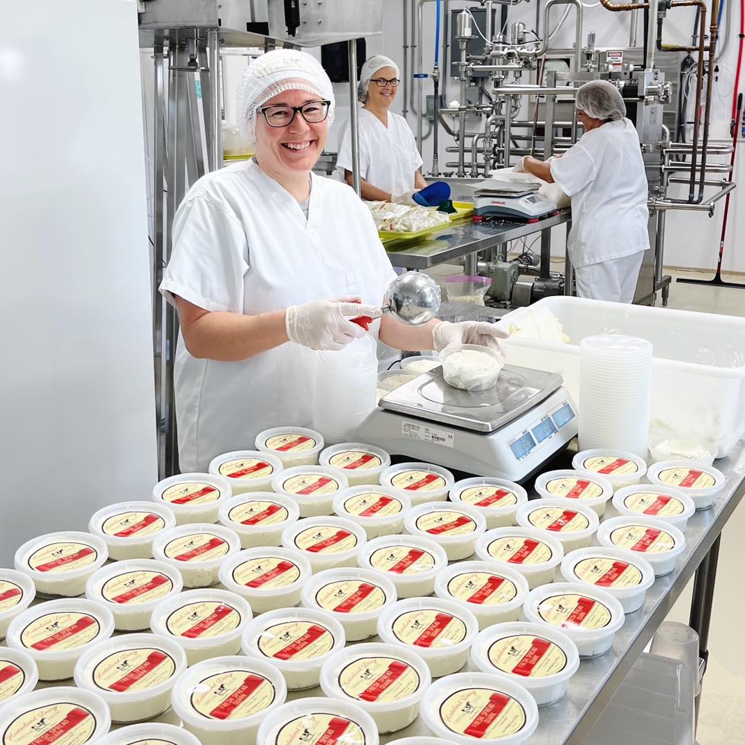 Worker filling containers with cheese at a dairy